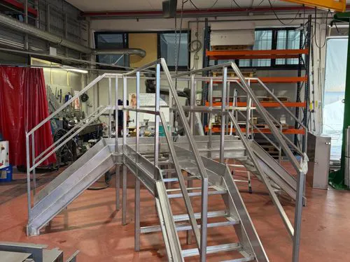 Scala in acciaio inox con passerella per scavalcare un macchinario industriale